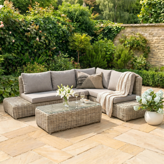 Outdoor patio set with wicker furniture and cushions on a stone patio.