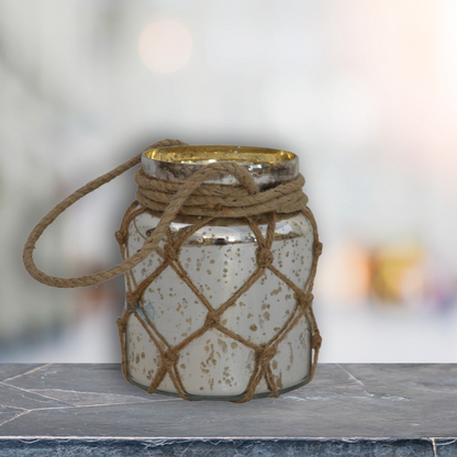 This small jar lantern has been made from vintage glass in an antiqued mercury finish. Update your home decor by displaying this piece using the rope that it comes with which has a natural fiber hanging loop.  It can be used as an accessory or be gifted to family and friends.