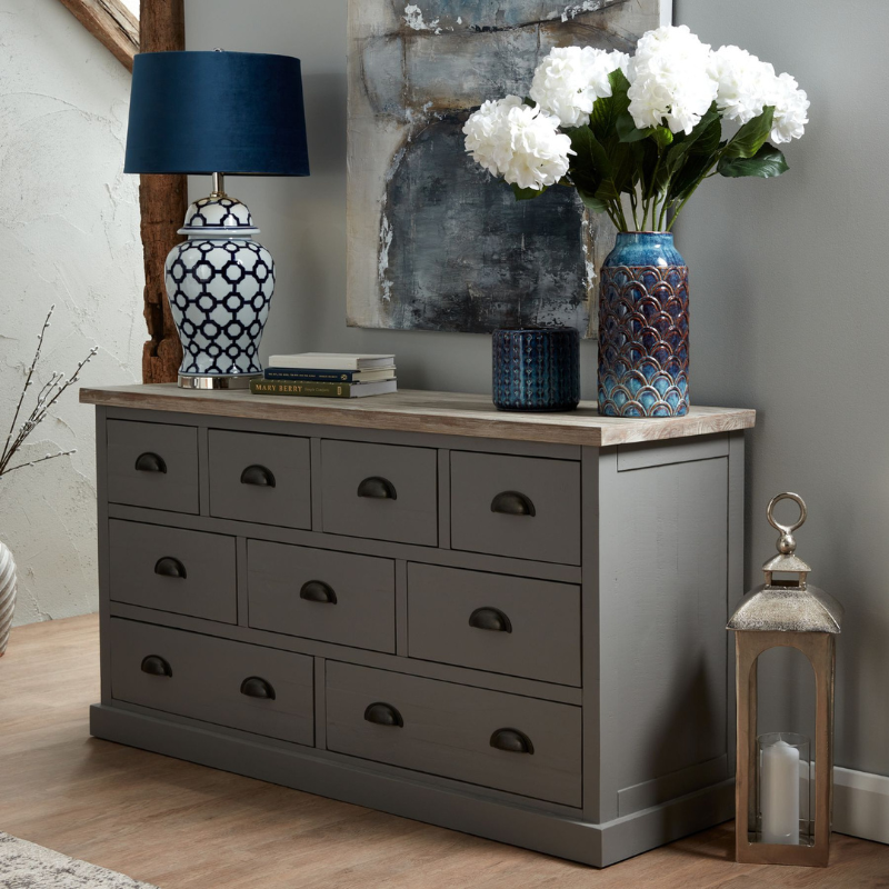 The Oxley Collection Nine Drawer Chest is perfect for display as well as storage. A washed wood plank surface blended with a frame in a warm grey hue deliver a relaxed, informal feel to any space. Stylish as well as functional, this high quality item would be equally at home in traditional and contemporary styled spaces. Style with a couple of lamps to really highlight its beauty.